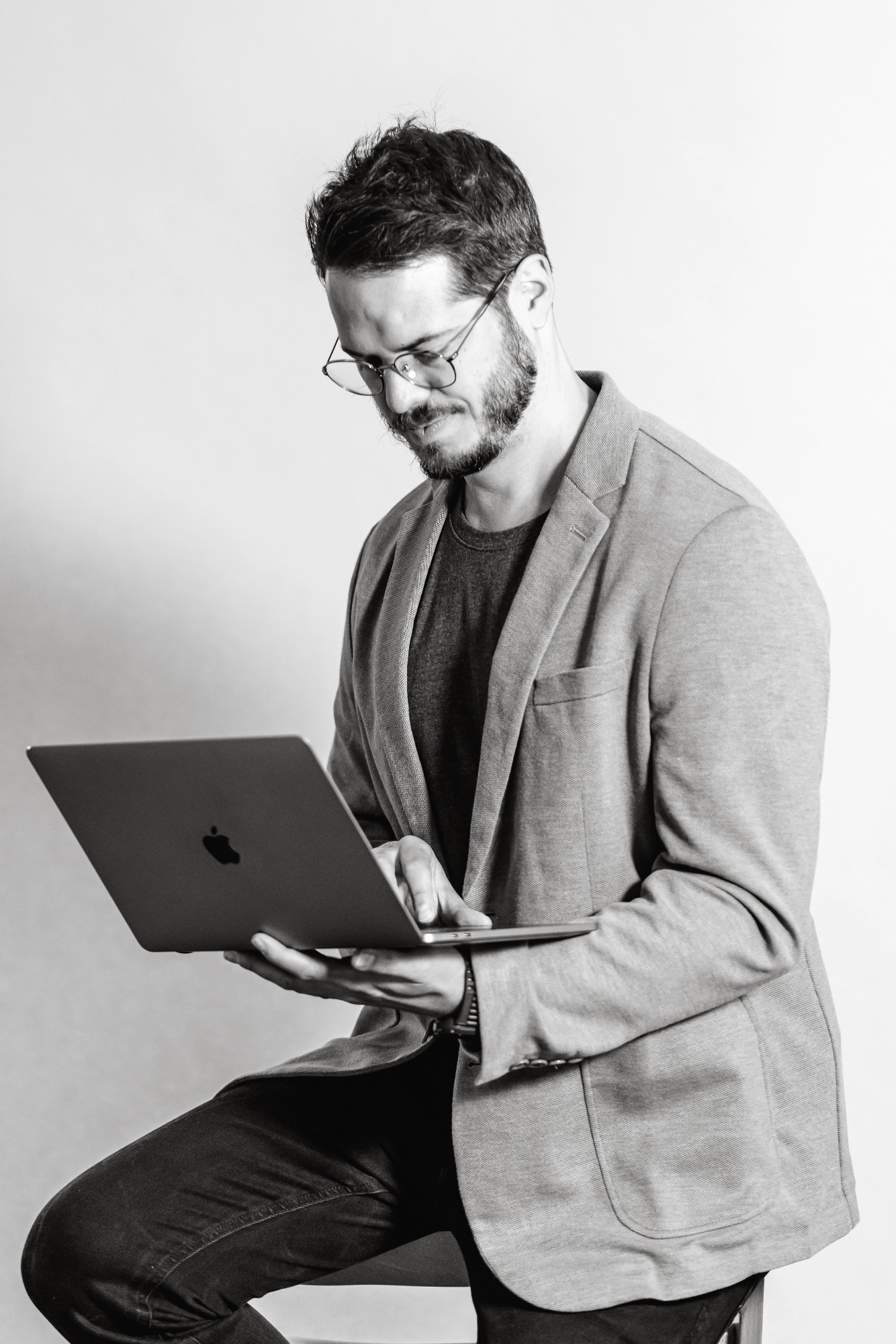 Carsten Kien sitzt auf einem Hocker und schaut in sein MacBook, was er in der Hand hält